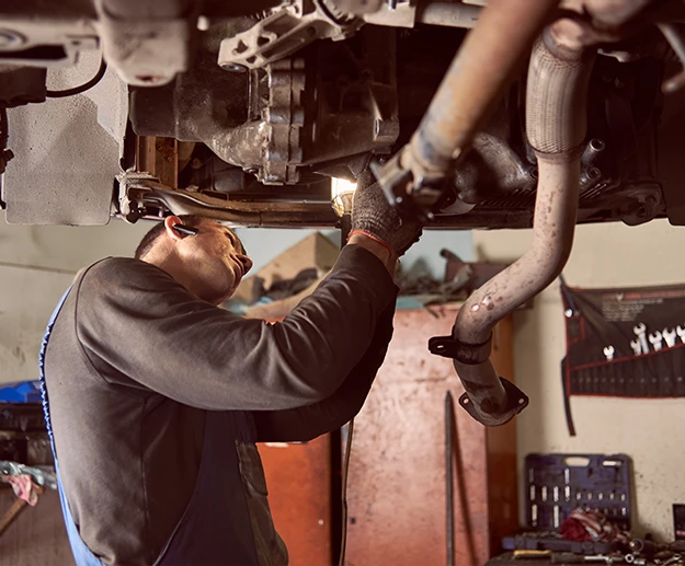 Mechanic repairing the exhaust system of a vehicle